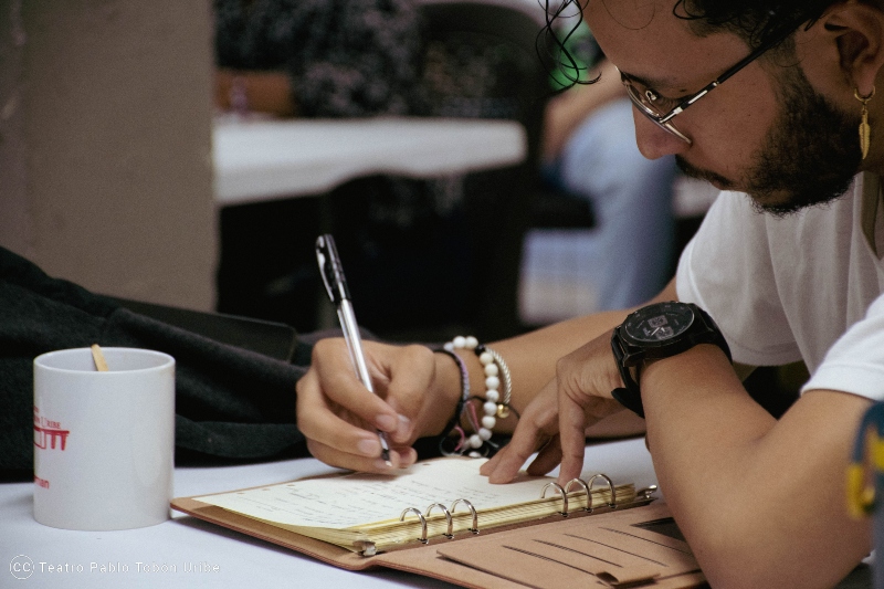 Hombre escribiendo en una agenda con un lápiz